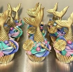 three cupcakes decorated with gold and blue icing are sitting on a table