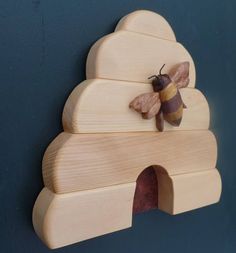 a wooden wall mounted with a bee on it's back and another insect sitting on the top