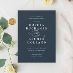 the wedding stationery is laid out on top of a table with white flowers and greenery