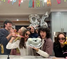 a group of people standing around a birthday cake