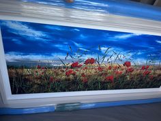 a painting of red poppies in a field with blue sky and clouds behind it