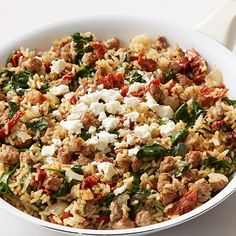 a white bowl filled with rice, meat and spinach on top of a table