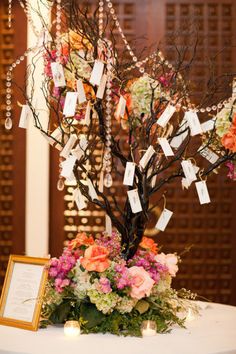 a tree with flowers and cards attached to it is sitting on top of a table