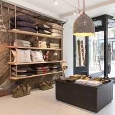 the inside of a shoe shop with lots of shoes on shelves and hanging lights above them