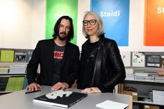 two people standing next to each other in front of a table with books on it