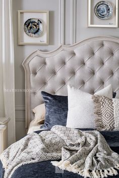 a bed with pillows and blankets on top of it in a bedroom next to two framed pictures