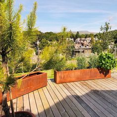 two large metal planters sitting on top of a wooden deck