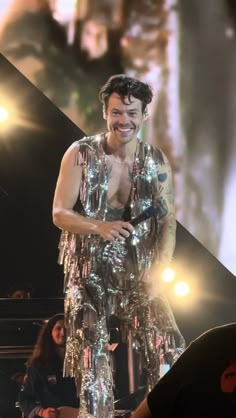 the man is dressed in silver and smiling for the camera while he stands on stage