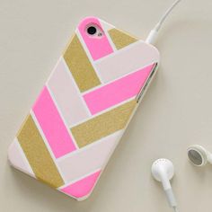 a pink and gold phone case sitting on top of a white table next to headphones