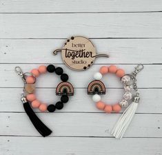 three bracelets with tassels and charms on top of a white wooden table