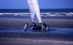 a sailboat that is sitting in the water at the beach with it's sails down