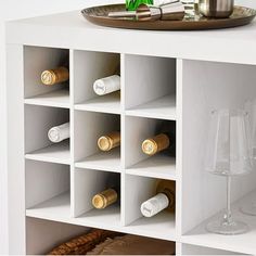 a white cabinet with wine bottles and glasses on the top shelf next to a plate