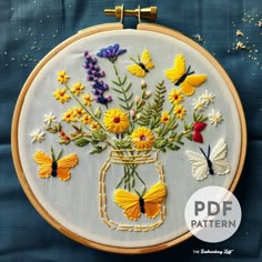 a embroidery pattern with flowers and butterflies in a mason jar on a blue fabric background