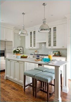 a kitchen with white cabinets and an island in the middle, along with two stools