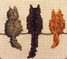 three different colored birds on a white background cross - stitched together with brown and orange threads