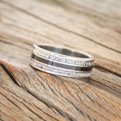 a silver ring with white and black stripes on it sitting on a wooden table top