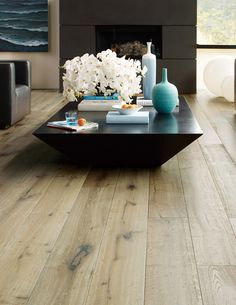 a living room filled with furniture and a fire place next to a large window on top of a hard wood floor