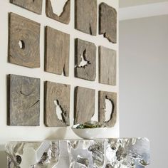 several pieces of wood are arranged on the wall above a bowl and vase in front of them