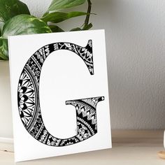 a black and white letter g on a table next to a potted green plant