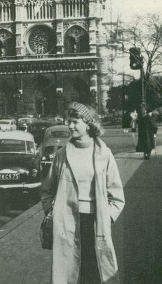 an old black and white photo of a woman walking down the street