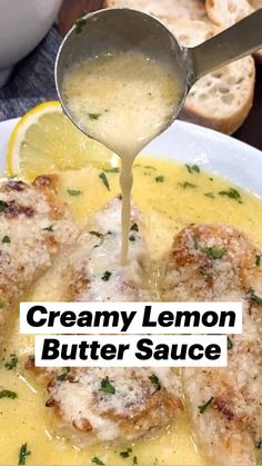 a spoon pouring gravy on some meat in a bowl with bread and lemon wedges