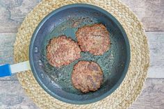 three hamburger patties cooking in a frying pan