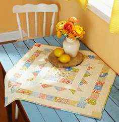 there is a vase with flowers and lemons on top of a table in front of a window