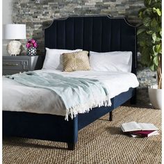 a bed with a blue headboard and pillows on top of it next to a lamp