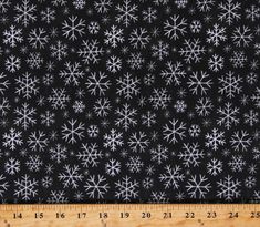 black and white snowflakes on a wooden surface with a ruler in the foreground