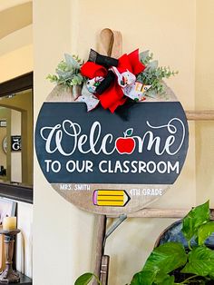 a welcome sign hanging from the side of a wall next to a potted plant