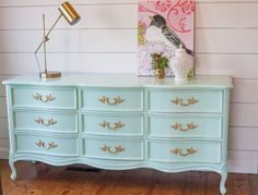 a blue dresser with gold handles and knobs on it's drawers in a room