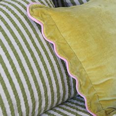 two green and white striped pillows with pink trims on the edges, sitting next to each other