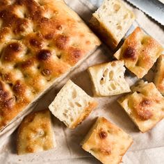 several pieces of bread sitting on top of a piece of paper next to a knife