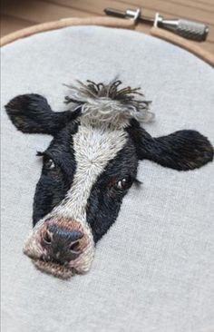 a black and white cow's head is embroidered on a hoop