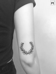 a woman's arm with a tattoo on it that has leaves in the shape of a wreath