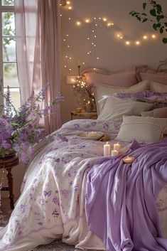 a bed covered in purple sheets and pillows next to a window with lights on it