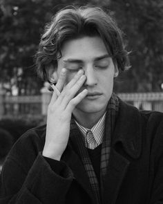 black and white photograph of a young man holding his hand to his face with both hands