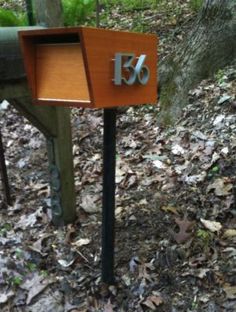 a mailbox with the number thirty written on it in front of some trees and leaves