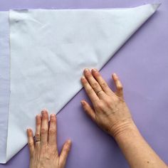 two hands on top of a piece of white paper next to a pair of scissors