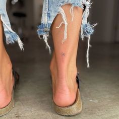 a woman's legs with torn up jeans and heels