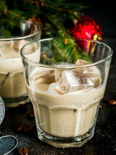 two glasses filled with ice sitting on top of a table next to a christmas tree