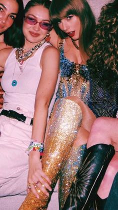 three women are posing for the camera in front of a wall with gold sequins