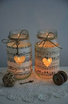 two mason jars with musical notes and heart lights in them on a lace doily