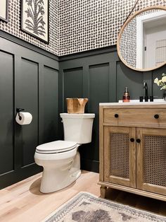 a white toilet sitting in a bathroom next to a wooden cabinet and mirror on the wall