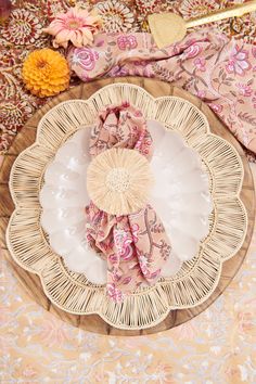 a white plate topped with pink napkins on top of a wooden platter next to an orange flower