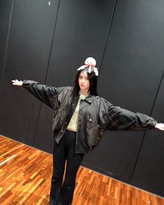 a woman standing on top of a hard wood floor holding her arms out in the air