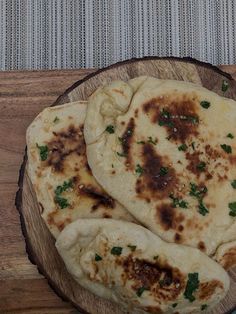 three pita breads sitting on top of a wooden plate