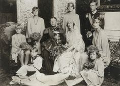 an old black and white photo of people dressed in formal clothing posing for the camera