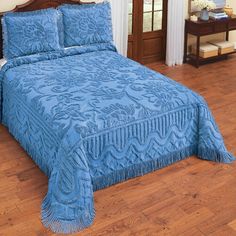 a bed with blue bedspread and pillows on top of it in a room