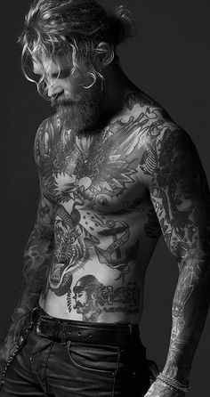 a man with tattoos and piercings on his chest standing in front of a black background